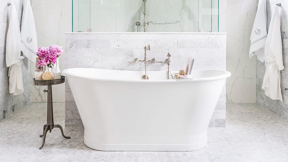 Cast iron freestanding tub in modern bathroom with marble tile